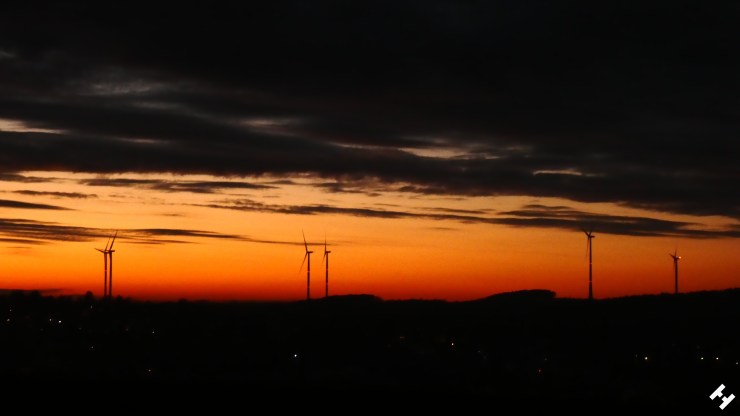 Rotgefärbter Himmel über dem Pleißetal mit Windrädern und der Erhebung am Sahnstau